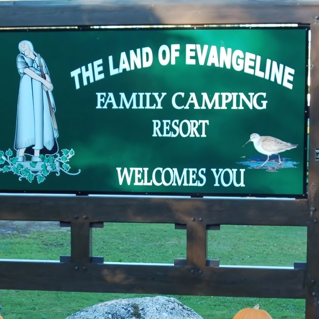 Green sign reads "The Land of Evangeline Family Camping Resort Welcomes You," with illustrations of a woman, a bird, and decorative flowers.