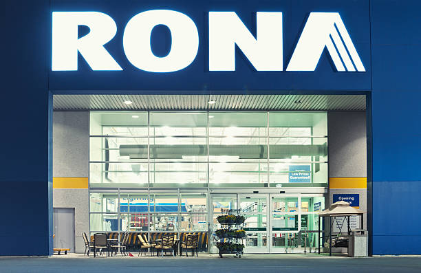 The exterior of a RONA hardware store at night, with illuminated signage and outdoor furniture displayed near the entrance.